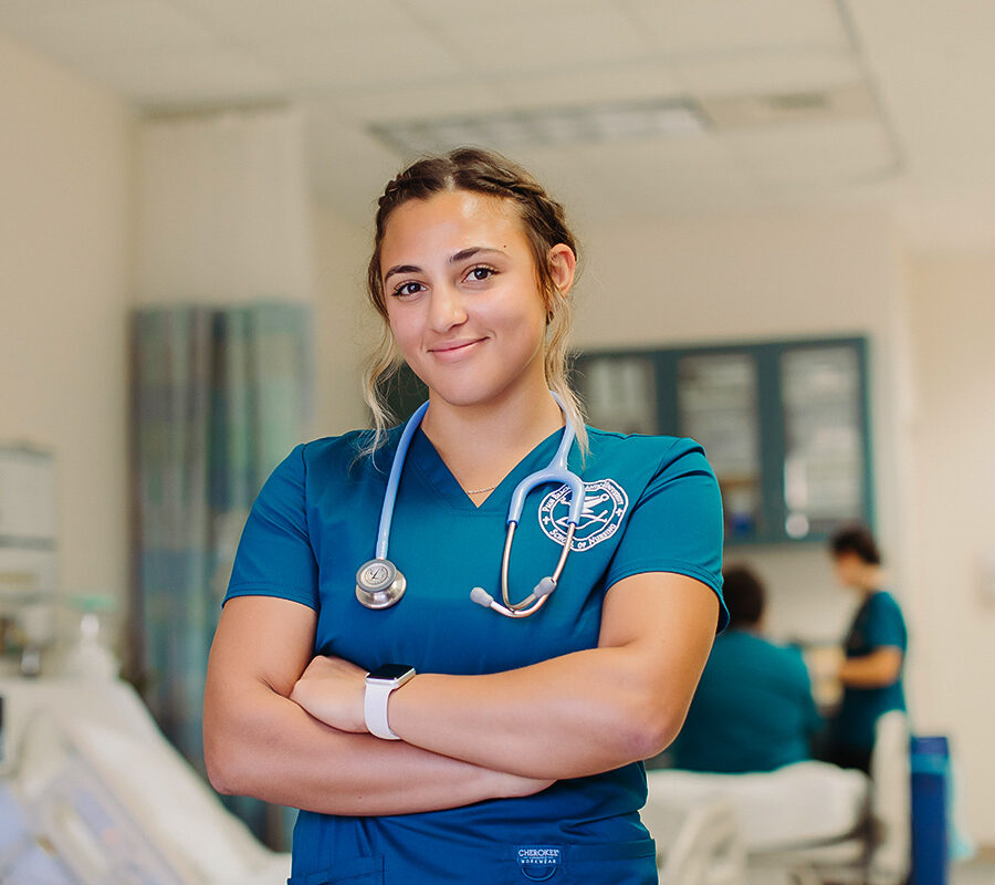 a nursing student wearing scrubs and a stethoscope smiling