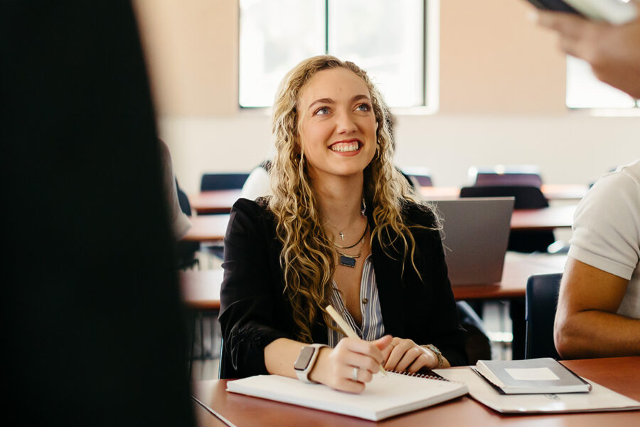 Creative writing student writes in a notebook in a classroom.