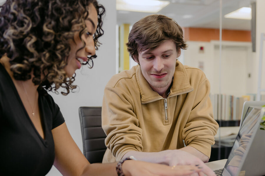 Two business administration students study together at a laptop