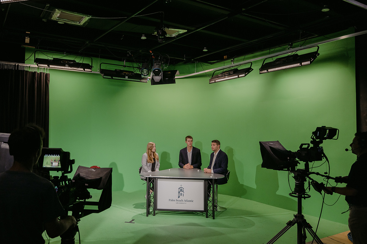 Sports broadcasting students present in front of a green screen.