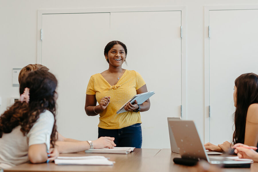 a smiling student presents in class to other students