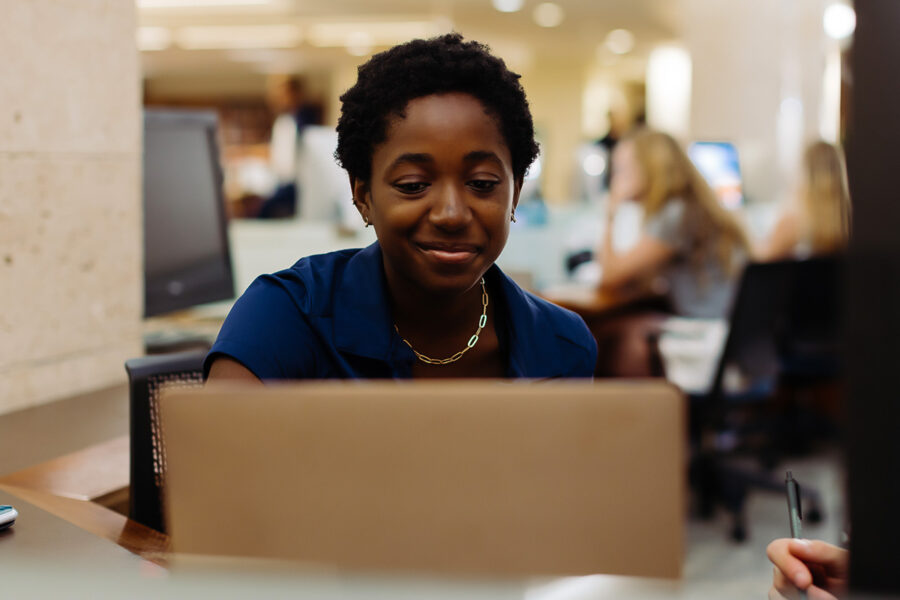 A PBA student works on a laptop in the library.