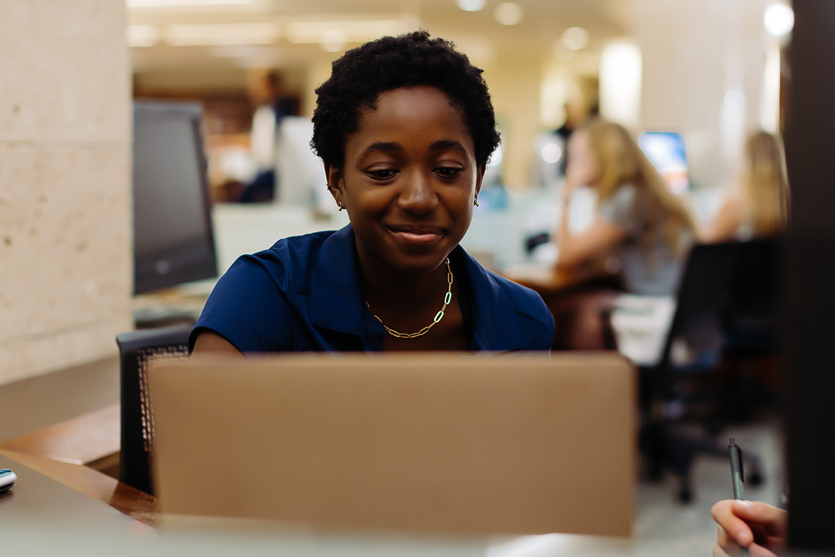 A PBA student works on a laptop in the library.