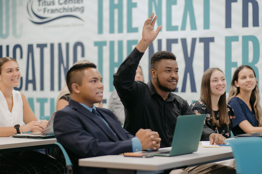 Student raises his hand in classroom lecture.