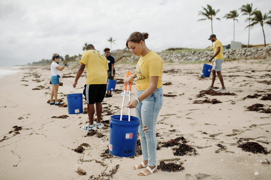 students studying Botany Environmental Science and Field Biology by collecting trash on the beach