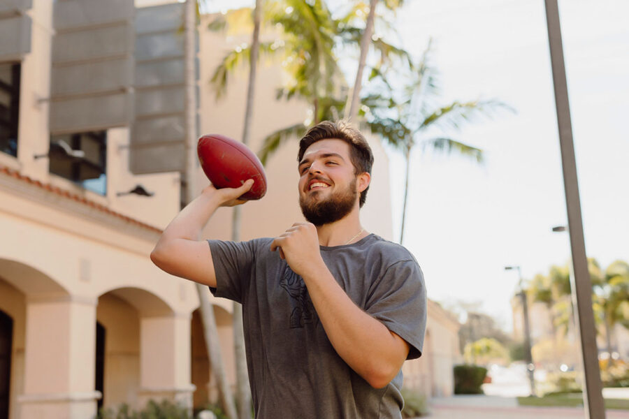 physical education student throws a football on campus.