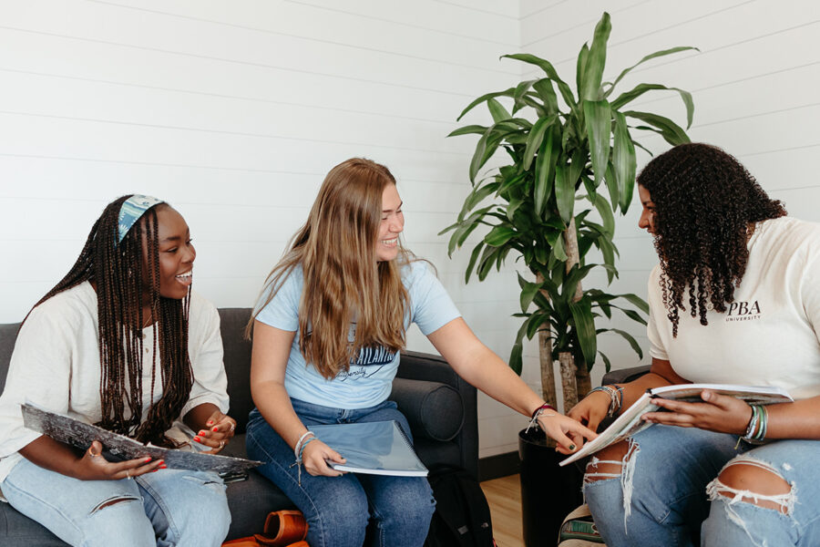 Three PBA students study together on campus.