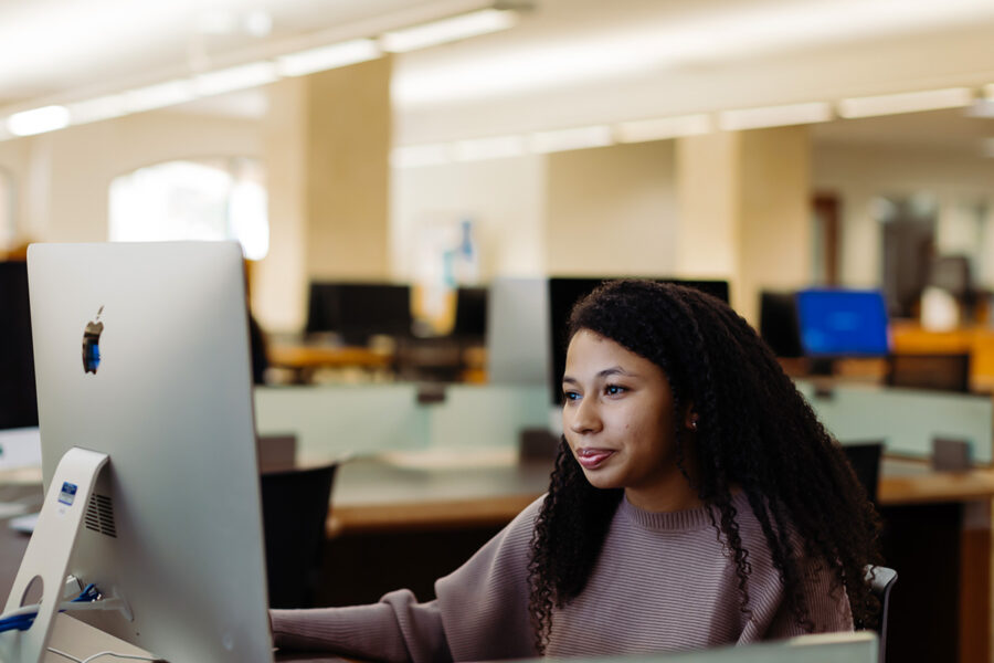 graphic arts and graphic design student uses a computer in the library.