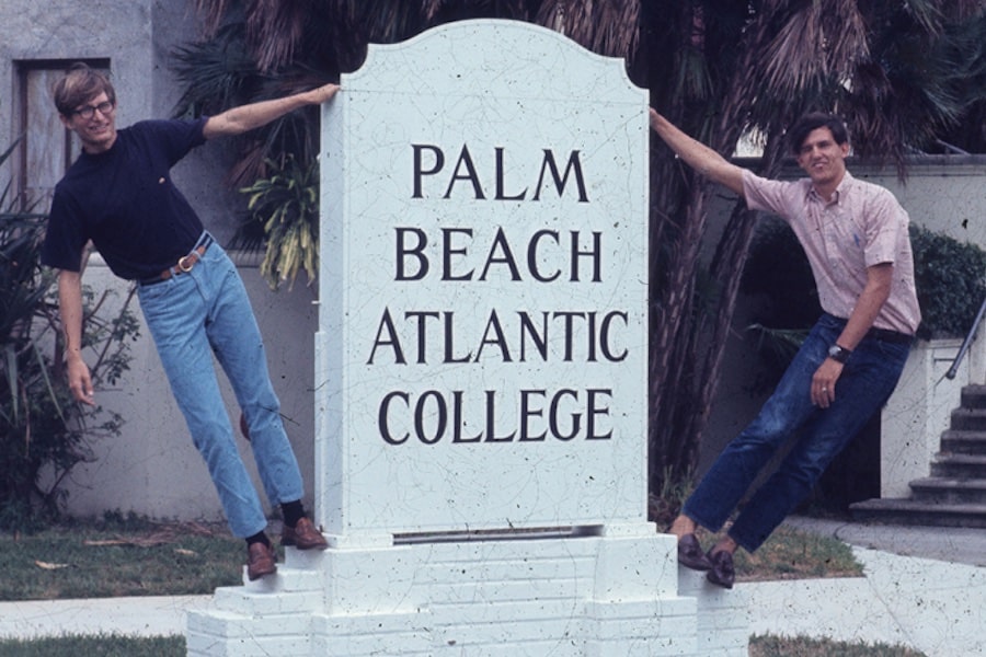 Two male posing next to college signage in the early days of Palm Beach Atlantic College