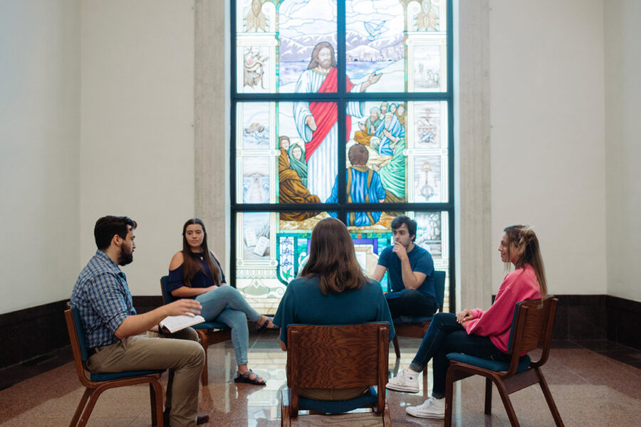 Ministry students sit in a circle and study the bible in a chapel.