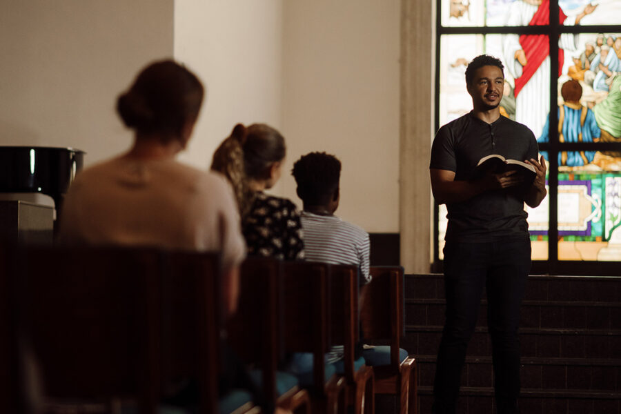 Student reads the bible at the front of chapel.