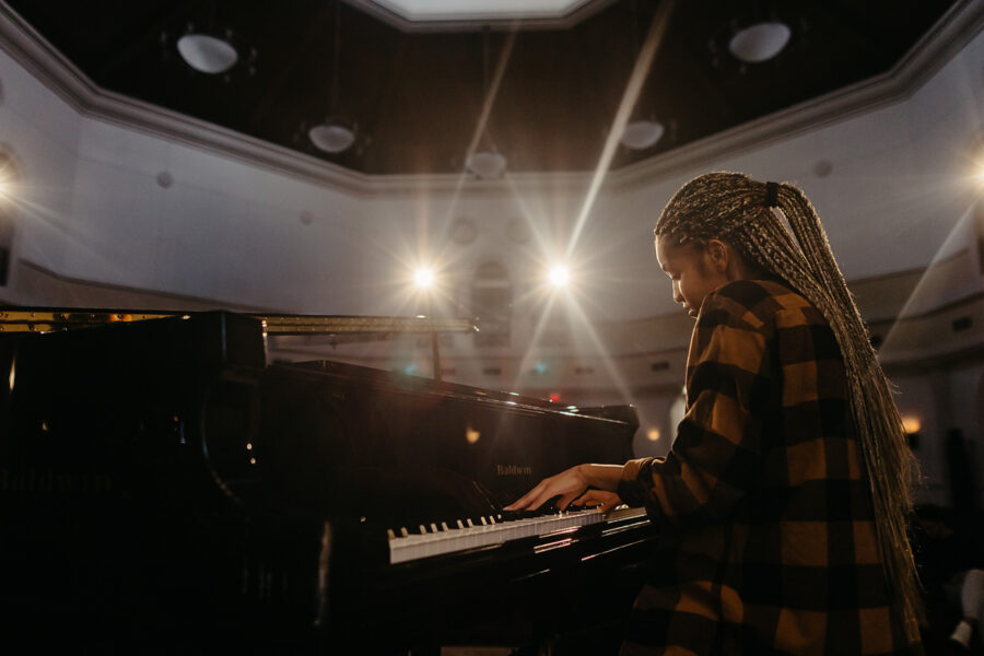 Music student plays the piano in an auditorium.