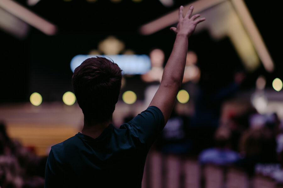 Christian community development minor student raises hand in chapel.