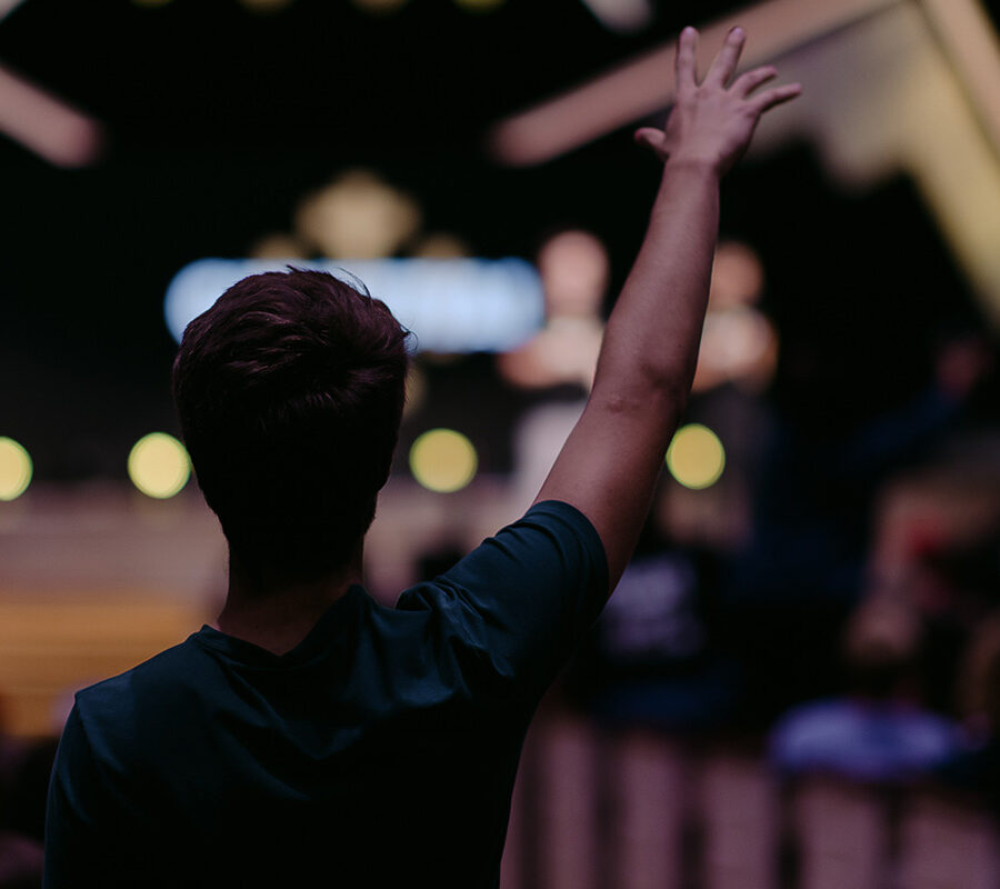 Christian community development minor student raises hand in chapel.