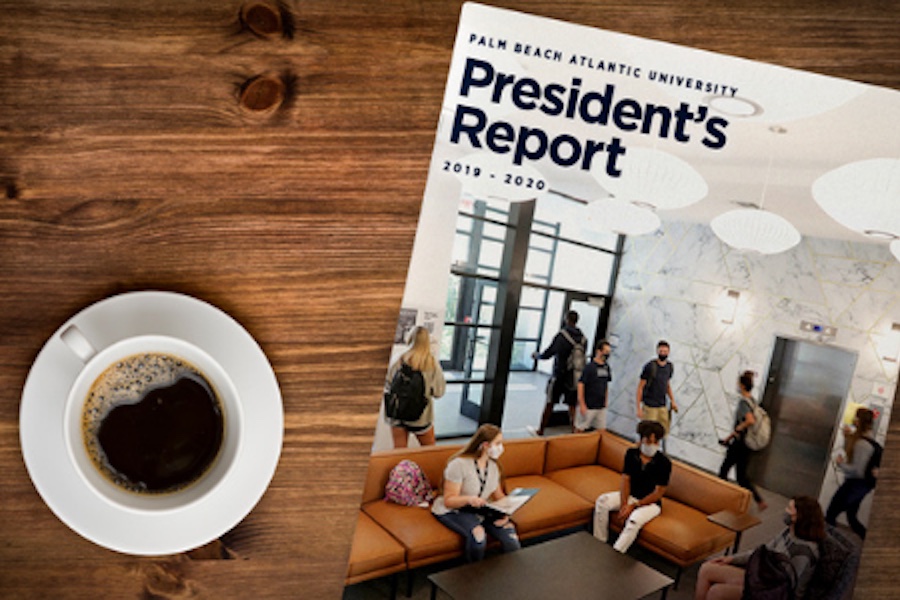 A copy of the Palm Beach Atlantic University's President's Report laying on a table next to a cup of coffee