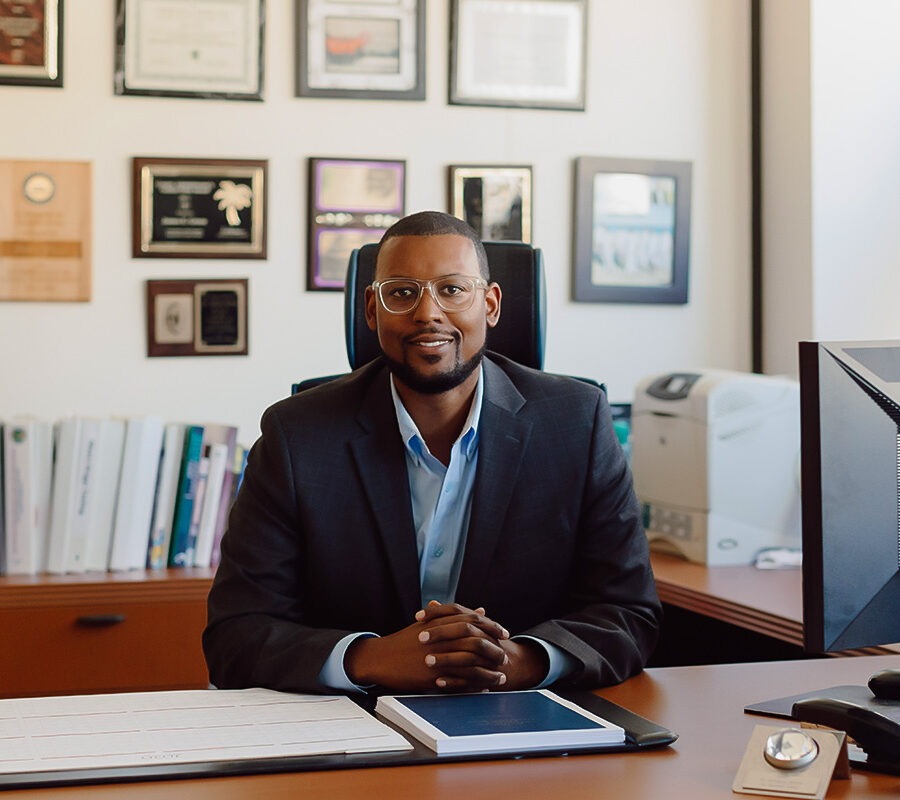 a faculty member sitting behind a desk smiling