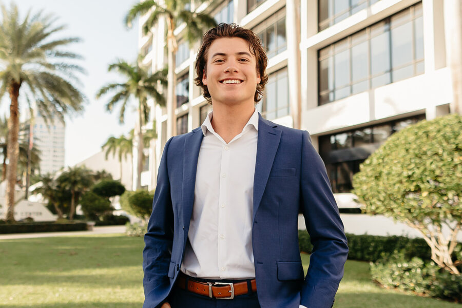 a male student standing outside of a building on campus at Palm Beach Atlantic University