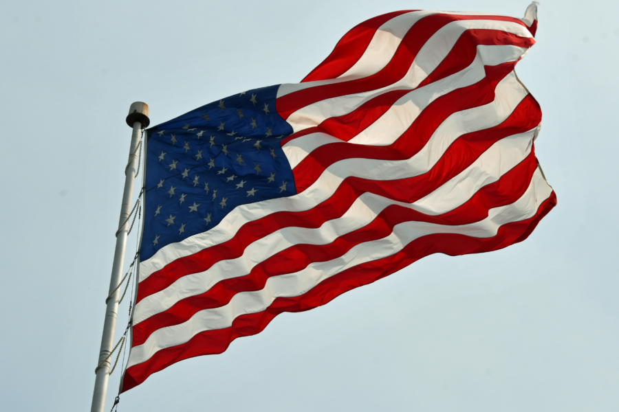 An image of the American flag flowing in the wind against the sky. A symbol of independence day