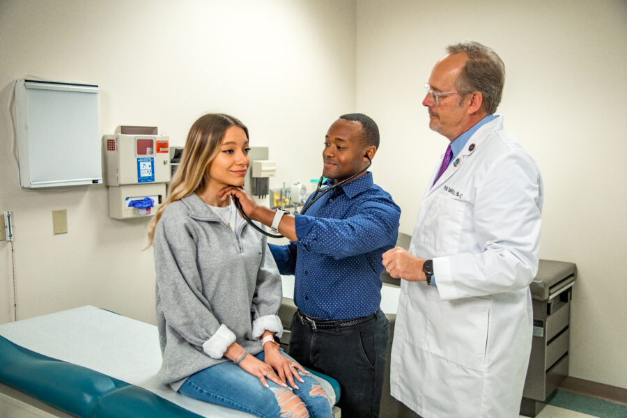 A photo of two doctors using a stethoscope on a patient