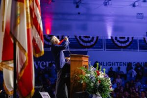 Thomas Peterffy raises his medal in the air.