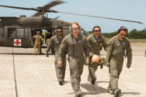 Luis Benitez carries a stretcher from a military helicopter with his team.