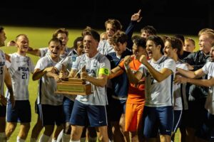 Palm Beach Atlantic University's men's soccer team holds trophy and celebrates winning Sunshine State Conference regular season.