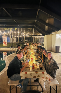 Palm Beach Atlantic University students enjoy a family-style Thanksgiving meal at a long table.