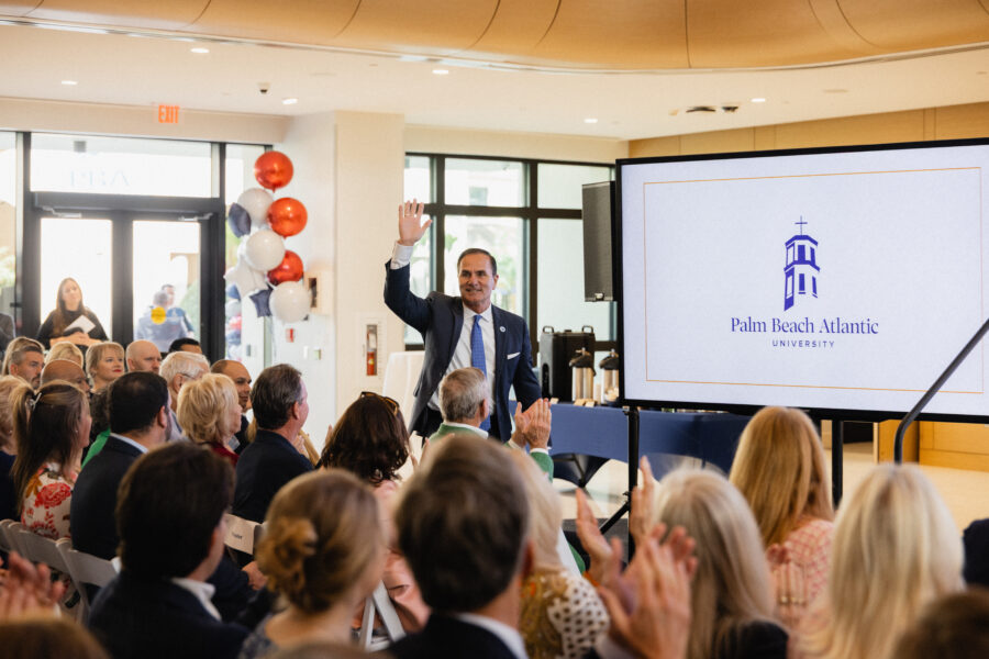 Man waves to crowd at grand opening of Marshall and Vera Lea Rinker Business Hall.
