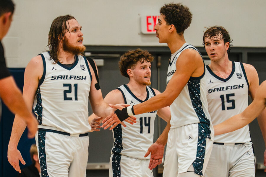 Photo from ShotByDan shows Palm Beach Atlantic University basketball players celebrating on the court.