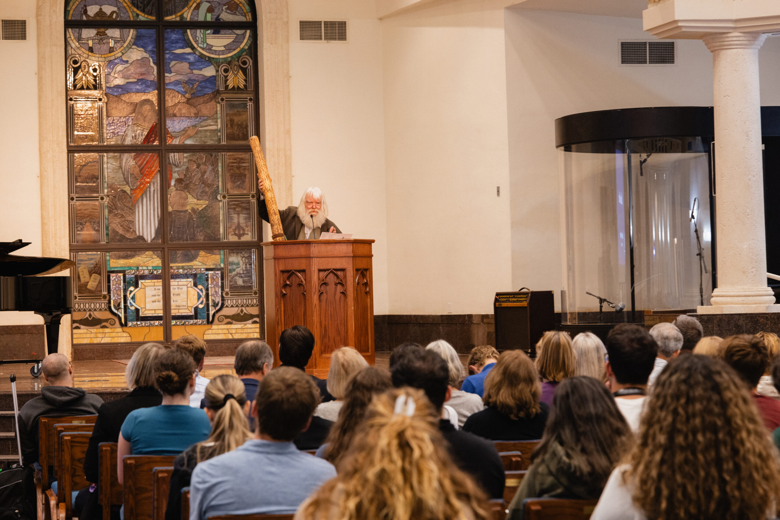 Malcolm Guite holds a rainstick while lecturing in Palm Beach Atlantic University's DeSantis Family Chapel.