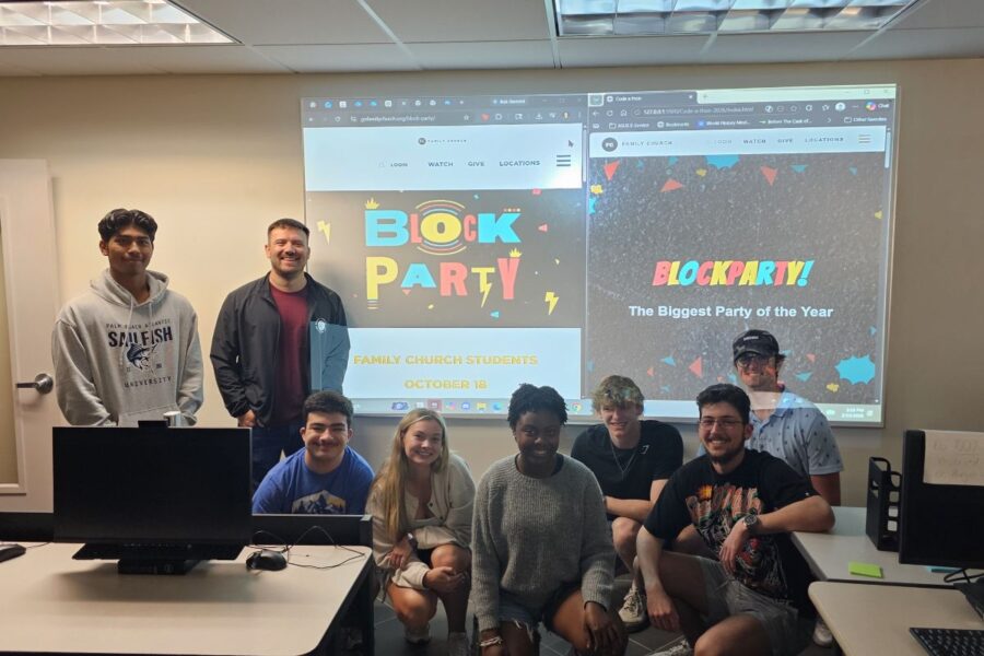 Palm Beach Atlantic University students and Pastor Jacob Kimbrell pose in front of a projection of their updated website design.