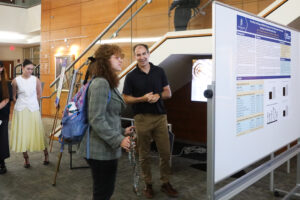 man and woman observe a research poster on a board