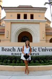 Palm Beach Atlantic University graduate Payton Aldridge poses in front of University sign.