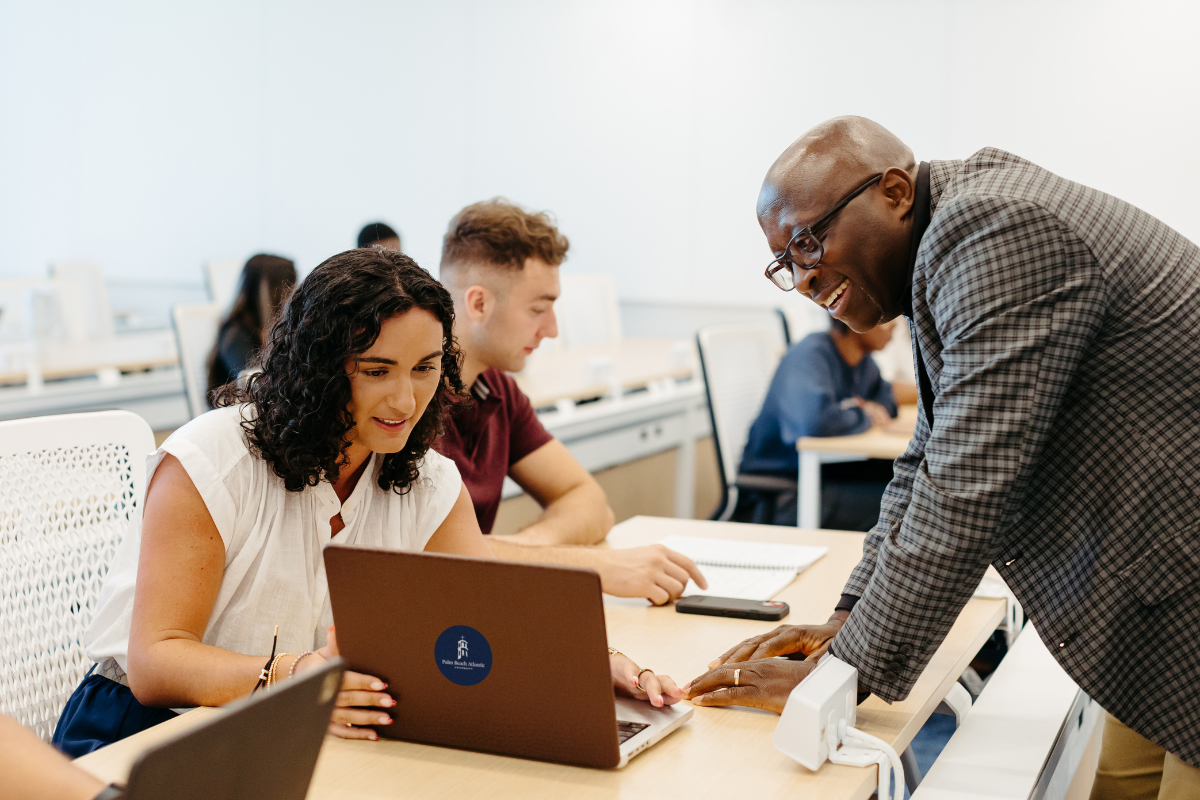 student showing a professor something on a laptop