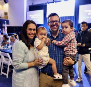 Winner of the Employee of the Year Award smiles with family at Community Day Assembly.